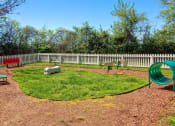 Thumbnail 28 of 49 - Pet park at the Retreat apts at Indian Lake  in hendersonville with dog agility course, red park bench, and white picket fence.