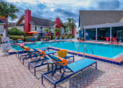 Thumbnail 37 of 60 - Fusion Orlando apartments community pool and large pool house next to two story apartment buildings with red chimneys