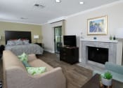 Thumbnail 17 of 60 - Fusion Orlando studio apartment spacious living area with built in fireplace, tan couch, teal sitting chair, and modern reading lamp.