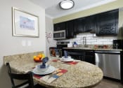Thumbnail 14 of 60 - Fusion Orlando studio apartment kitchen with espresso cabinets and stainless steel microwave, electric stove, dishwasher, and fridge.