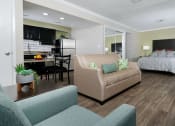Thumbnail 13 of 60 - Fusion Orlando furnished studio apartment with large bed with night stands, spacious living room area, and kitchen with breakfast nook.