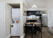 Thumbnail 9 of 60 - Fusion Orlando apartment kitchen with pantry and dinette next to in unit laundry washer and dryer and carpeted stairs leading up.