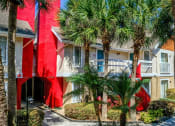 Thumbnail 43 of 60 - Fusion Orlando apartments exterior shot of buildings with red chimneys and balconies with white railing surrounded by palm trees