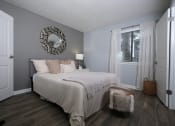 Thumbnail 14 of 43 - Fusion Fort Worth apartment in Haltom City bedroom with large window with gauze drapes and large bed with cozy bedding and modern fur footstool.