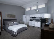Thumbnail 17 of 43 - Fusion Fort Worth (previously Desert Sands apartments) efficiency studio apartment living area with grey carpet and grey plank flooring in modern kitchen area.