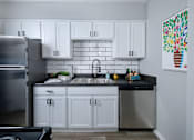 Thumbnail 5 of 36 - Kitchen in Stadium 700 apartments in Arlington TX with stainless steel appliances, white luxury cabinets, and white subway tile backsplash.
