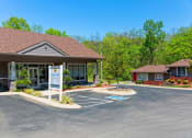 Thumbnail 46 of 49 - The Retreat at Indian Lake in Hendersonville leasing office exterior with parking lot and next door apartment building surrounded by green trees.