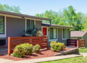Thumbnail 40 of 49 - The Retreat apts at Indian Lake in Hendersonville exterior. Apartments are single story with grey siding, red front door, and stained wood fence on patios.