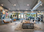 Thumbnail 30 of 52 - A modern office space with a large table and chairs in the foreground and a view of the outside through the windows at Fusion Hollywood.