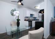 Thumbnail 5 of 23 - Fifteen Fifty smoke free apartments Las Vegas open concept dining area and kitchen with white cabinets and modern glass dining table with white orchid