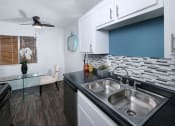 Thumbnail 2 of 23 - 1550 apartments kitchen in Las Vegas, 89119. White cabinets with modern silver pulls, dishwasher, and grey tone tile backsplash.