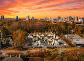 Thumbnail 17 of 18 - A sunset view of a city skyline with buildings and trees in the foreground at Fusion Buckhead Apartments Atlanta.