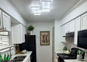 Thumbnail 4 of 36 - Fusion Crossroads kitchen with white cabinets and a black refrigerator.