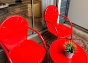Thumbnail 8 of 36 - Fusion Crossroads patio with two red chairs and a small table with a plant on it.