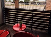 Thumbnail 9 of 36 - Fusion Crossroads balcony with a red table and chairs overlooking a parking lot.