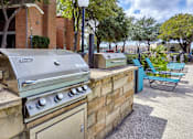 Thumbnail 10 of 32 - A BBQ grill is on a patio with a blue chair and a brick wall at 1601 Eastchase Pkwy in Fort Worth, TX.