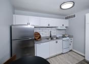 Thumbnail 13 of 43 - Fusion Fort Worth efficiency apartment in Haltom City kitchen with white dishwasher and stove, stainless steel refrigerator, and subway tile backsplash.