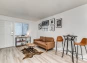Thumbnail 1 of 43 - Fusion Fort Worth (previously Desert Sands Apartments) renovated apartment in Haltom City, TX living room with light wood plank flooring and camel colored midcentury modern furniture and decor.