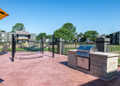Thumbnail 24 of 43 - barbecue area and hammock lounge at Fusion Fort Worth in Haltom City, TX next to large green field with black iron fence.