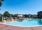 Thumbnail 23 of 43 - Community swimming pool at Fusion Fort Worth apartments in Haltom City, TX with yellow inflatables and lounge chairs with umbrellas