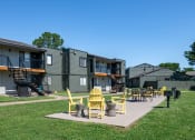 Thumbnail 29 of 43 - outdoor patio at fusion fort worth apartments with lawn, barbecue, and yellow patio furniture