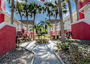 Thumbnail 35 of 41 - A red and white building with a palm tree in front at Fusion Orlando furnished apartments.
