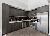 Thumbnail 17 of 52 - Fusion Hollywood apartments modern kitchen with dark wood cabinets and stainless steel appliances.