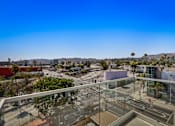 Thumbnail 25 of 52 - A view of Los Angeles from a private balcony at Fusion Hollywood overlooking a city street with buildings and palm trees.