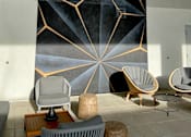 Thumbnail 15 of 18 - Fusion Hollywood Apartments (previously Alta Ink Apartments) seating area with a large geometric mural on the wall and several chairs and tables.