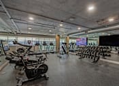 Thumbnail 31 of 52 - Fusion Hollywood fitness center with a row of stationary bikes and a TV screen.