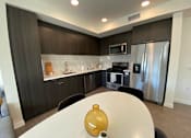 Thumbnail 2 of 18 - Fusion Hollywood Apartments with modern kitchen with a table and chairs in the foreground.