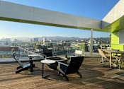 Thumbnail 12 of 18 - Fusion Hollywood rooftop deck with a table and chairs overlooking a cityscape.