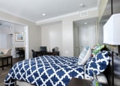 Thumbnail 2 of 60 - Fusion Orlando furnished apartment bedroom with large open door to living area. Bedroom has large bed with blue and white duvet and desk nook. Apartments in Orlando, FL.