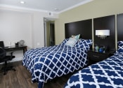 Thumbnail 4 of 60 - Fusion Orlando apartments Orlando, FL bedroom with two full beds with blue and white duvets, espresso headboards, and modern lamp and night stand between.