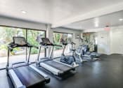 Thumbnail 11 of 15 - Fitness center in Fusion Warner Center apartments in Woodland Hills, CA with cardio machines facing out large sliding glass windows.