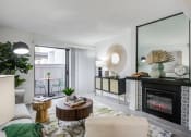 Thumbnail 2 of 15 - Fusion Warner Center luxury Woodland Hills apartments living room with elegant natural decor, electric tile fireplace and sliding glass door to patio.