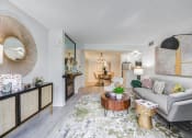 Thumbnail 1 of 15 - Fusion Warner Center luxury apartments in Woodland Hills ca living room with elegant natural decor - modern grey couch and mottled green, grey and blue rug.