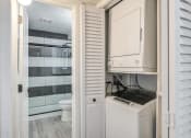 Thumbnail 8 of 15 - Fusion Warner Center luxury apartments in Woodland Hills in-unit laundry with top load washer and front load dryer in closet with shutter doors.