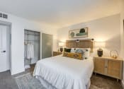 Thumbnail 5 of 15 - Fusion Warner Center Woodland Hills apartment. One bedroom apartment in Woodland Hills CA carpeted bedroom with frosted glass doors on closet and large bed with white boho duvet.