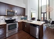 Thumbnail 1 of 24 - Fusion Encore Hollywood Apartments modern kitchen with dark wood cabinets and stainless steel appliances.
