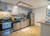 Thumbnail 1 of 49 - Kitchen in the retreat apts at Indian Lake in Hendersonville with grey cabinets, stainless steel appliances, and luxury wood style floors.