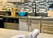Thumbnail 2 of 49 - Place setting on kitchen island in the retreat apts at Indian Lake in Hendersonville with blue and cream plates and sliver napkin with beaded flower napkin ring.