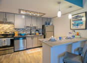 Thumbnail 3 of 49 - Kitchen in the Retreat apts at Indian Lake in Hendersonville with kitchen island and stainless steel electric stove, dishwasher, and fridge.