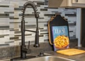 Thumbnail 5 of 49 - Kitchen sink in the Retreat apts at Indian Lake in Hendersonville with modern black matte faucet and greyscale tile backsplash.