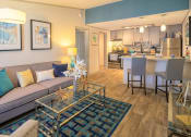 Thumbnail 8 of 49 - Open Concept living room and kitchen in the Retreat apts at Indian Lake in Hendersonville with large modern couch and blue geometric rug.