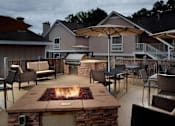 Thumbnail 11 of 18 - A patio with a fire pit and chairs.