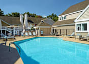 Thumbnail 9 of 18 - A large swimming pool surrounded by lounge chairs and buildings at Fusion Buckhead Apartments.