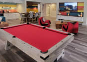 Thumbnail 60 of 60 - Fusion Orlando apartments clubhouse pool table with red felt and light grey wood in front of television center and next to coffee bar.
