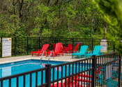 Thumbnail 23 of 49 - Community pool at the Retreat apartments at Indian Lake in hendersonville with red and blue lounge chairs and black iron fence.