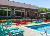 Thumbnail 22 of 49 - Community pool at the Retreat at Indian Lake apartments in hendersonville with red and blue Adirondack and lounge chairs